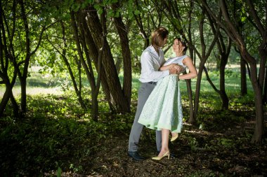 Düğün çifti, güzel genç gelin ve damat ayakta açık havada elele bir parkta gülümseyen