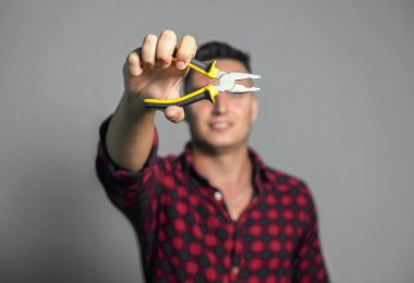 Genç holding pense gri arka plan üzerinde adam.