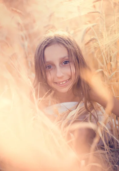 Niña feliz jugando en el campo de trigo al atardecer —  Fotos de Stock