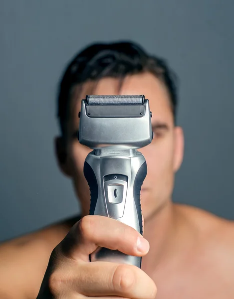 Mano sosteniendo una máquina de afeitar eléctrica — Foto de Stock