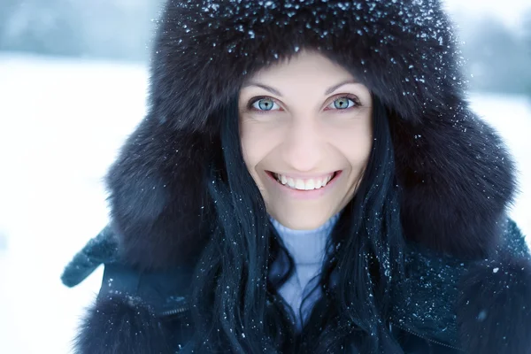 Jovem mulher em um capuz peludo nevado — Fotografia de Stock