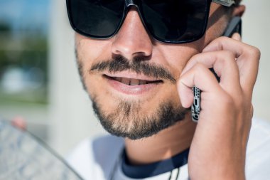 young man in sunglasses with beard talking on mobilephone