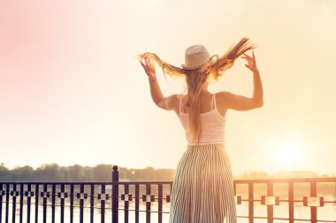 bir şehir Park'ta yürüyordunuz şapkalı mutlu kız. Gün batımında çekim. 