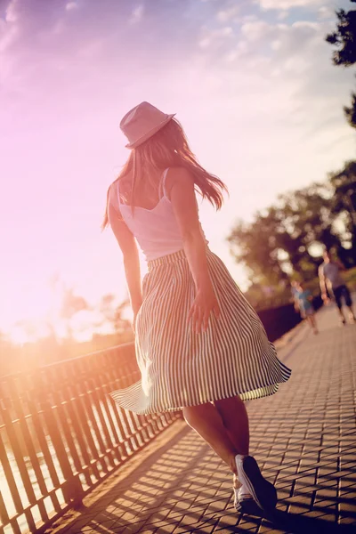 Szczęśliwa dziewczyna w kapeluszu spaceru w parku miejskiego. Strzelania na zachodzie słońca. — Zdjęcie stockowe