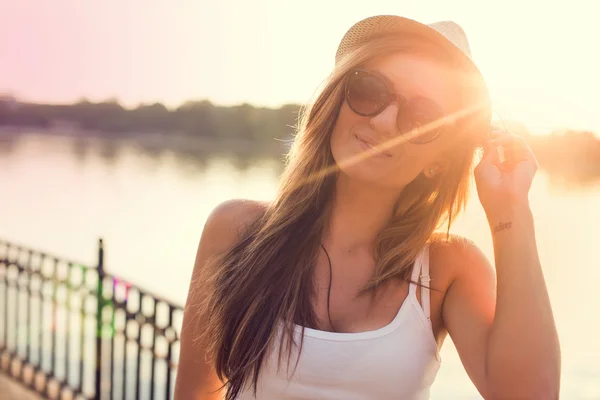 Chica feliz en un sombrero caminando en un parque de la ciudad. Disparos al atardecer . —  Fotos de Stock