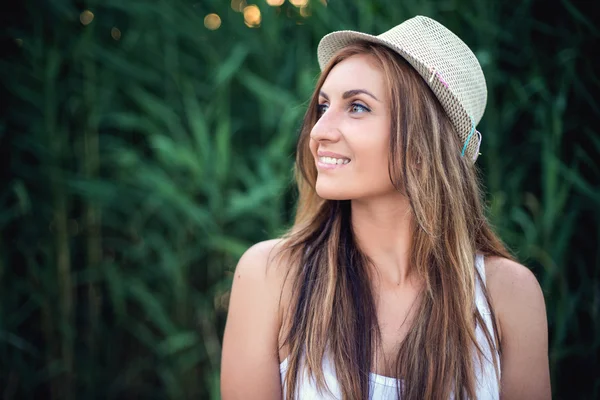 Retrato de una chica en un sombrero caminando en un parque de la ciudad. Disparos al atardecer . — Foto de Stock