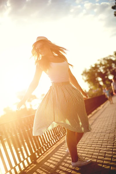 Chica feliz en un sombrero caminando en un parque de la ciudad. Disparos al atardecer . Fotos De Stock Sin Royalties Gratis
