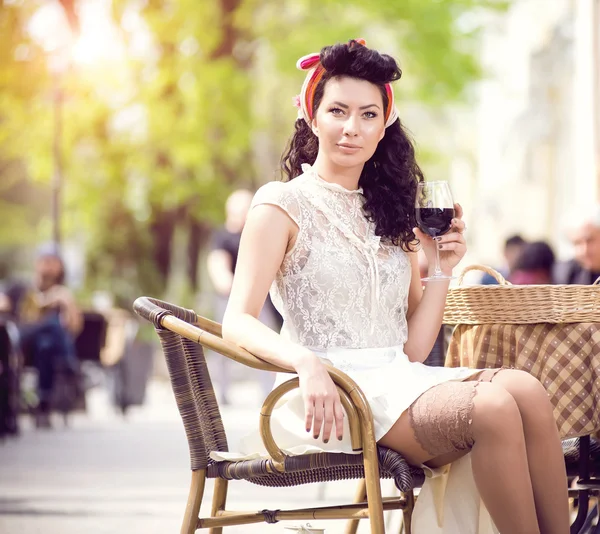 Bella ragazza con un bicchiere di vino rosso da solo in un caffè di strada — Foto Stock