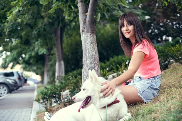 Mladá dívka a její husky venčení v městském parku. — Stock fotografie