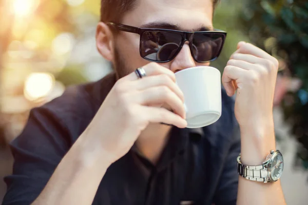 Hombre de negocios moderno bebiendo café en la cafetería de la calle en la puesta del sol — Foto de Stock