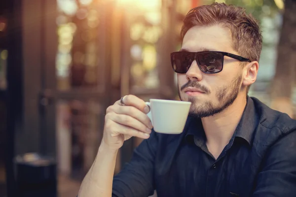 Moderner Geschäftsmann trinkt Kaffee im Straßencafé am Sonnenuntergang — Stockfoto