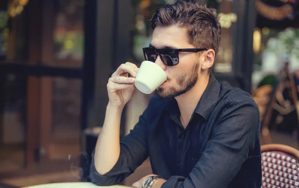 Cutie hombre con taza de café mirando el teléfono móvil al aire libre — Foto de Stock