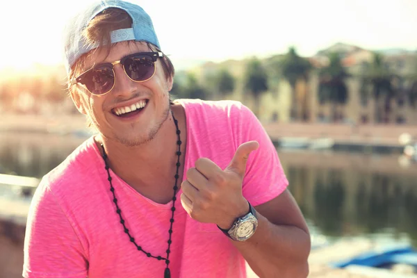 Happy man in hat and sunglasses smiling at the beach on the sunset