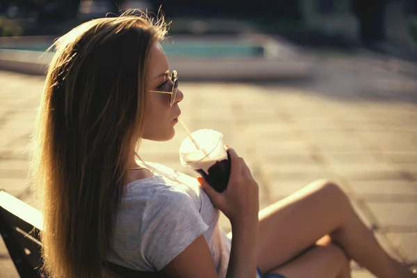 Söt leende flicka med mjölk shake sitter på bänken på gatan café — Stockfoto