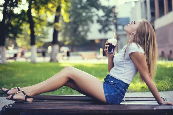 Söt leende flicka med mjölk shake sitter på bänken på gatan café — Stockfoto