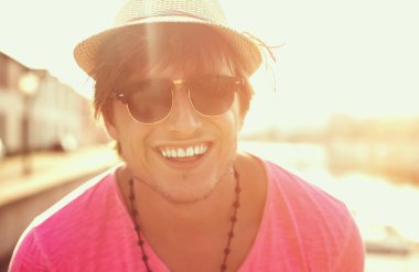 Mutlu bir adam sahilde sunset bulvarında gülümseyen güneş gözlüğü ve şapka