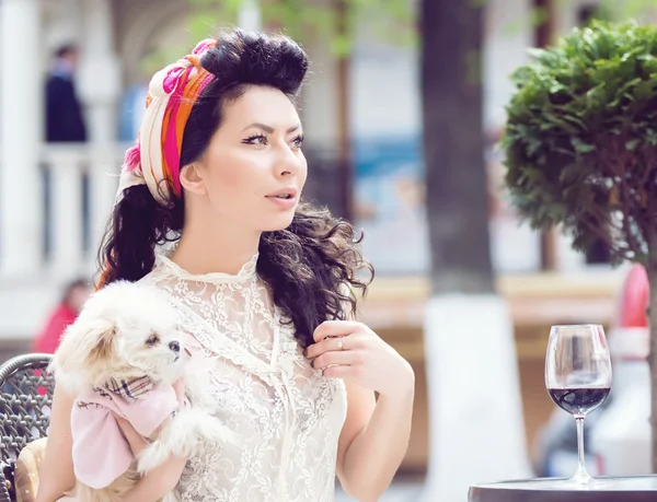 Молодая итальянская женщина с маленьким щенком, пьет красное вино в открытом кафе — стоковое фото
