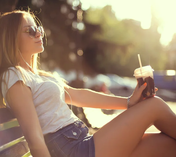 Söt leende flicka med mjölk shake sitter på bänken på gatan café — Stockfoto