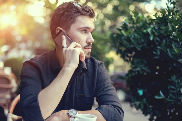 Man talking on the mobile phone in a coffee shop terrace outdoors