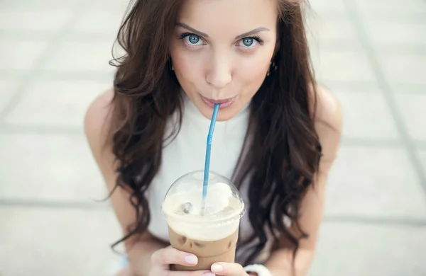 Feliz chica hermosa sentada en las escaleras en el parque y beber café helado — Foto de Stock