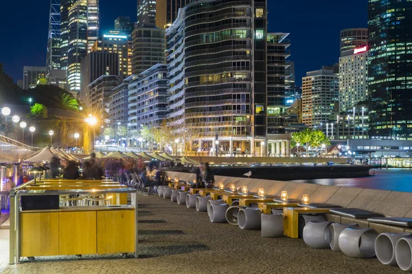 Café con gente y edificios iluminados por la noche — Foto de Stock