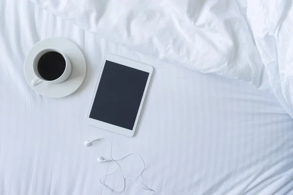 Kahve, tablet ve kulaklık yatakta