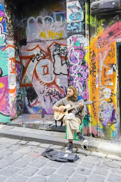 Street musician playing guitar in laneway