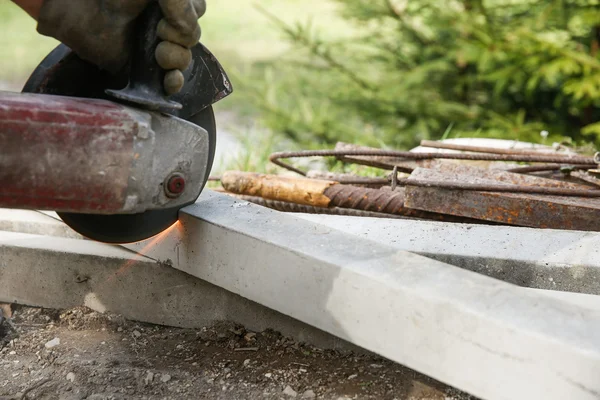 Trabalhador da construção cortando um pilar de concreto armado — Fotografia de Stock