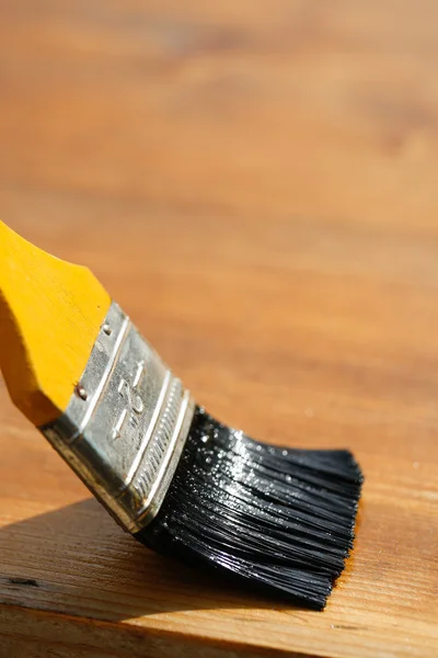 Paintbrush sliding over wooden surface, protecting wood — Stock Photo, Image