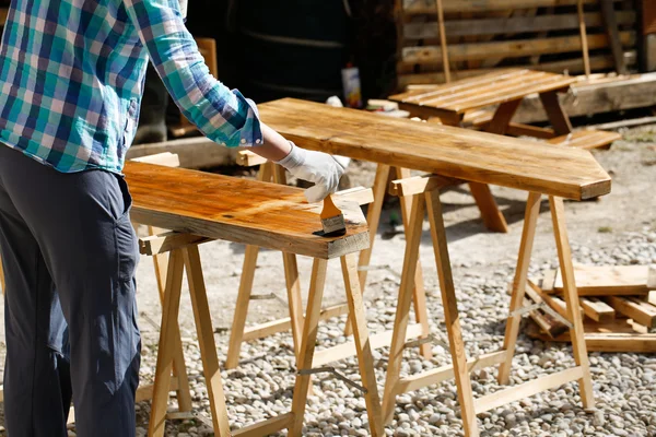 Lavoratore che applica vernice per il trattamento del legno fresco — Foto Stock