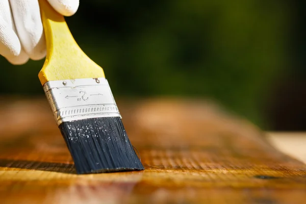 Paintbrush sliding over wooden surface, protecting wood — Stock Photo, Image