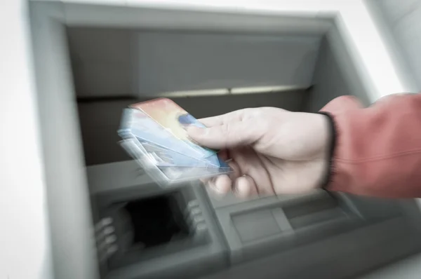Man at ATM machine with stash of credit and debit cards — Stock Photo, Image