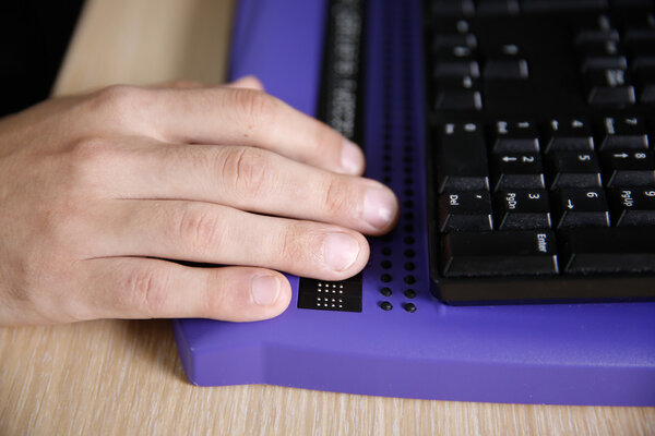 Blind person using computer with braille computer display 