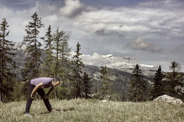 Hiker on a mountain top pasture exercising and stretching — Stock Photo, Image