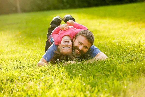 Ayah dan anak perempuan yang dikhususkan berbaring di rumput — Stok Foto