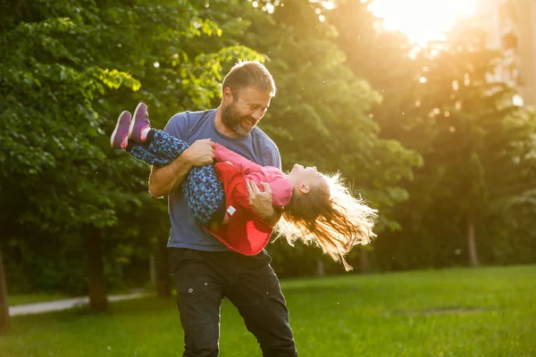 Dedicado pai girando sua filha em círculos — Fotografia de Stock