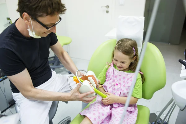 Girl in dentists chair tooth-brushing a model — Stock Photo, Image