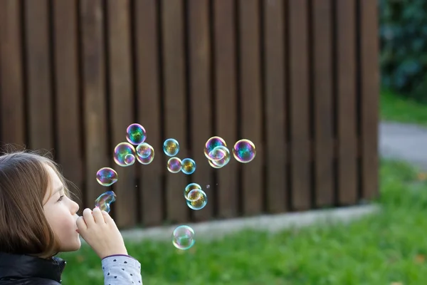 Malá holka fouká bubliny — Stock fotografie