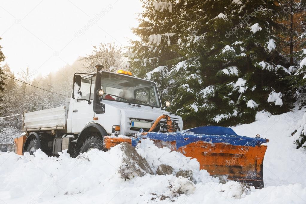 Snow plough making its way through the snowy country road