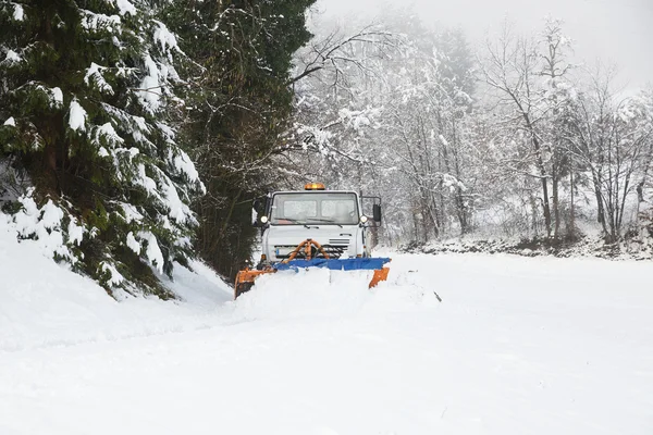 Arado de neve fazendo o seu caminho através da estrada do país nevado — Fotografia de Stock