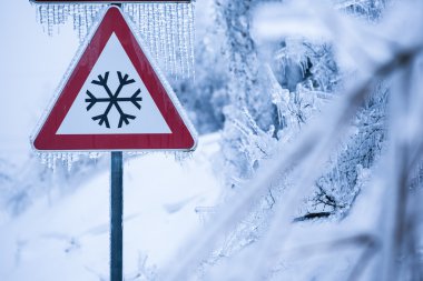 Ağaçlar karla karışık yağmur ile buzlu yol için trafik işaretleri kaplı