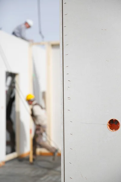 Tomas de corriente eléctrica en un panel de yeso con trabajadores en segundo plano — Foto de Stock