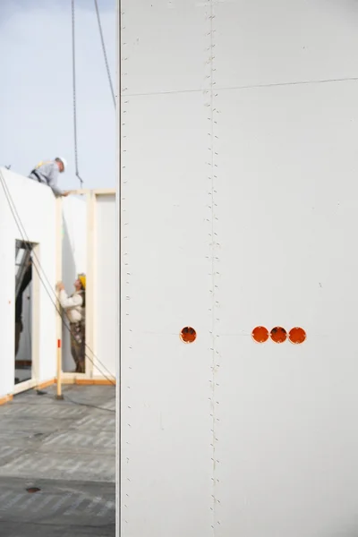 Electricity sockets in drywall with workers in background