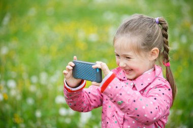 Little girl photographing with her smartphone clipart