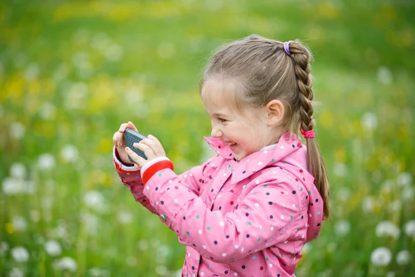 Маленька дівчинка фотографує зі своїм смартфоном — стокове фото