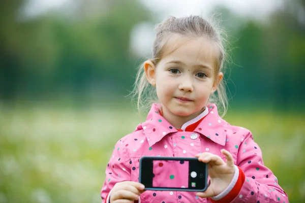 Holčička drží chytrý telefon s obrázkem na displeji — Stock fotografie