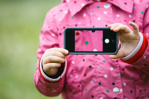 Little girl holding a smart phone with picture on display — Stock Photo, Image