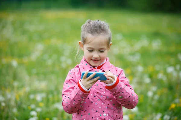 Girl watching cartoon and playing games on smartphone — Stock Photo, Image