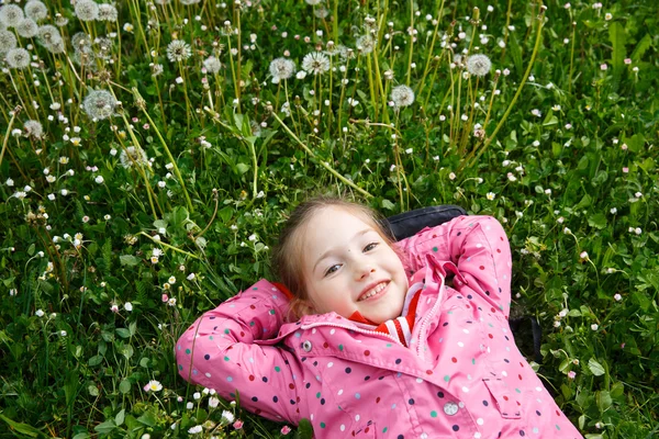 Fille couchée dans l'herbe, entourée de pissenlit — Photo