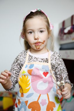 Little girl eating chocolate off the mixer beater  clipart